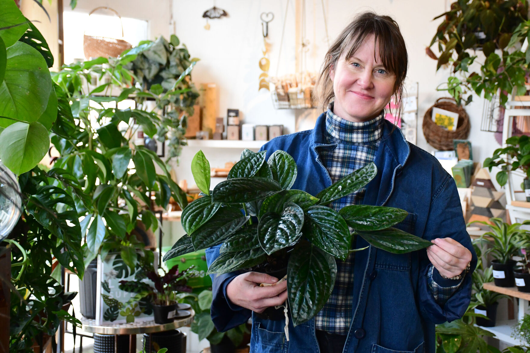 Yawn holds a plant as she poses in her store
